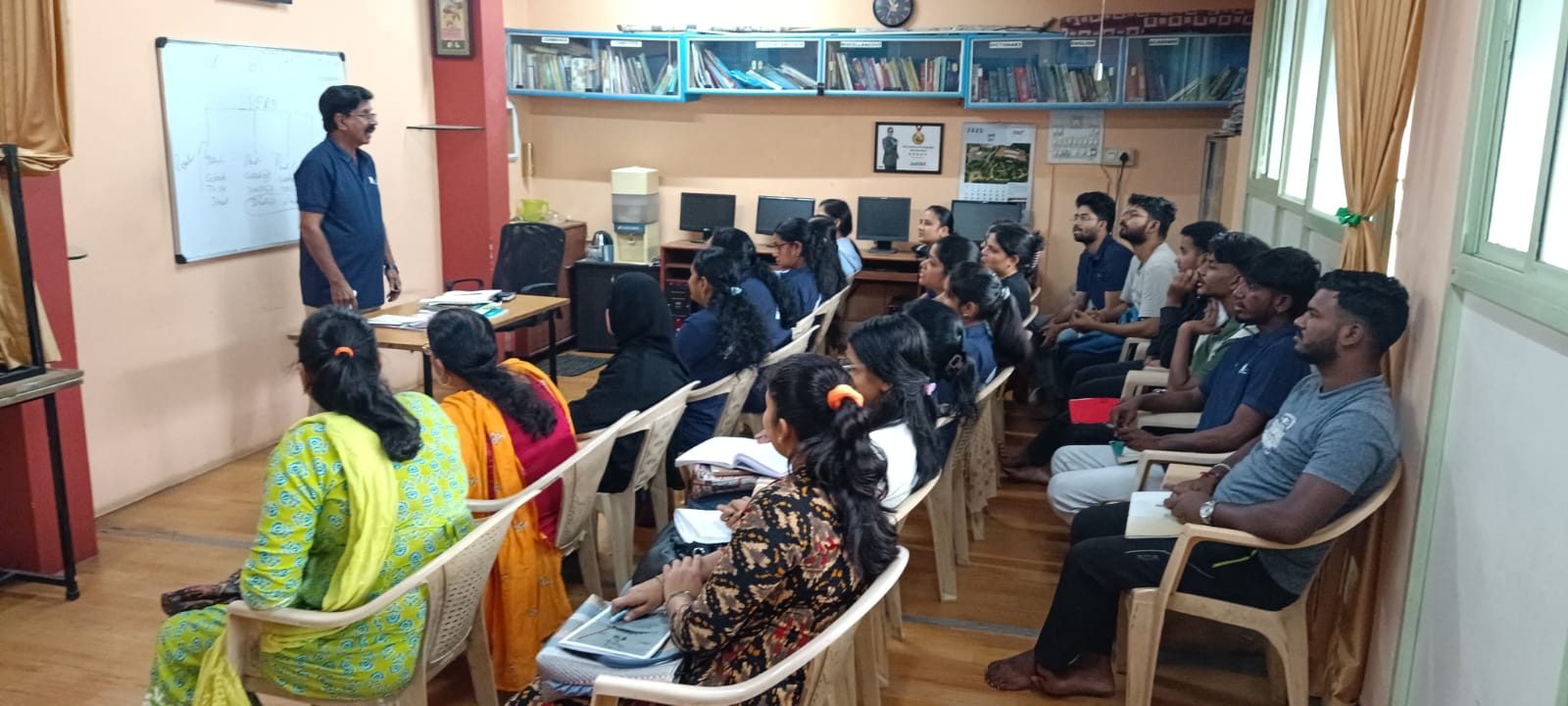 Trainer teaching at the whiteboard in a full classroom