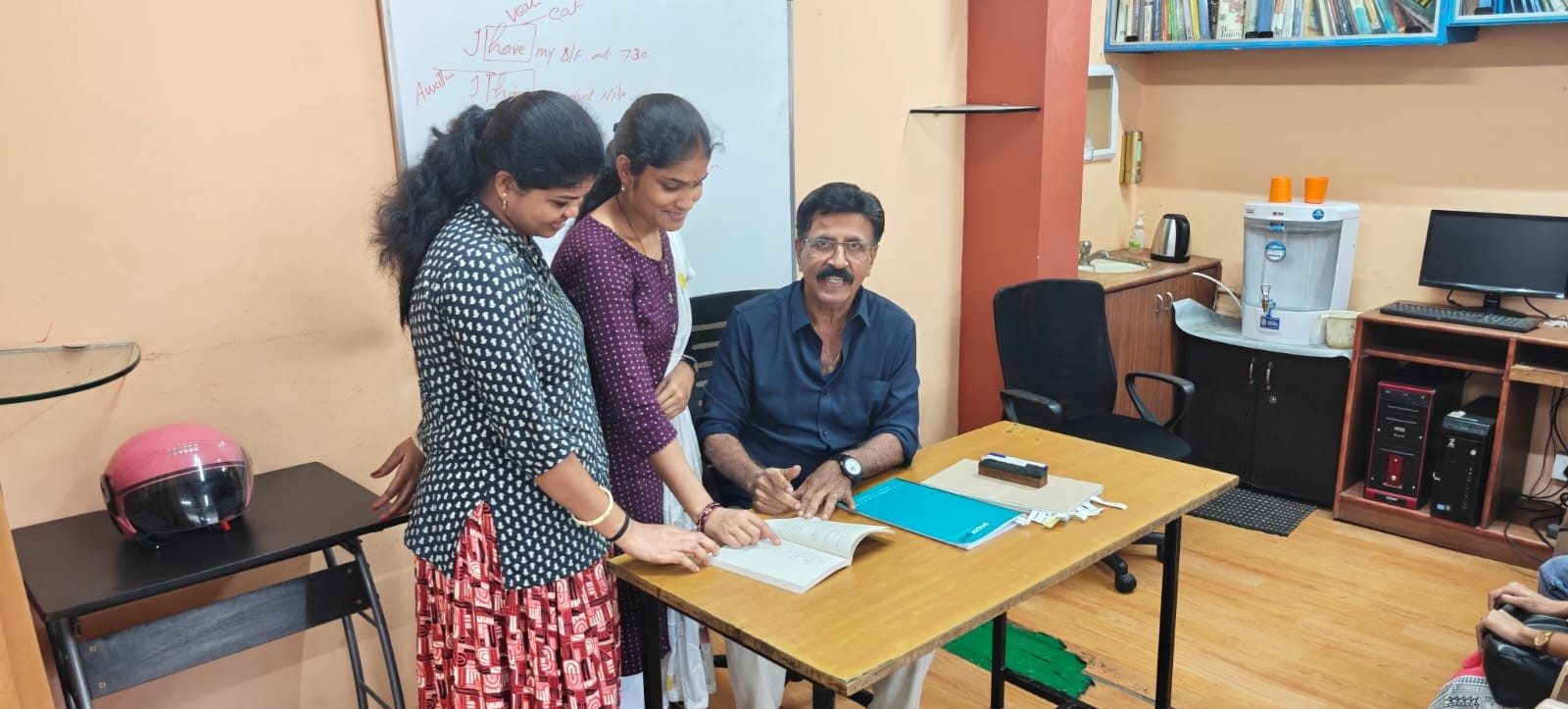 Trainer helping students with their course book